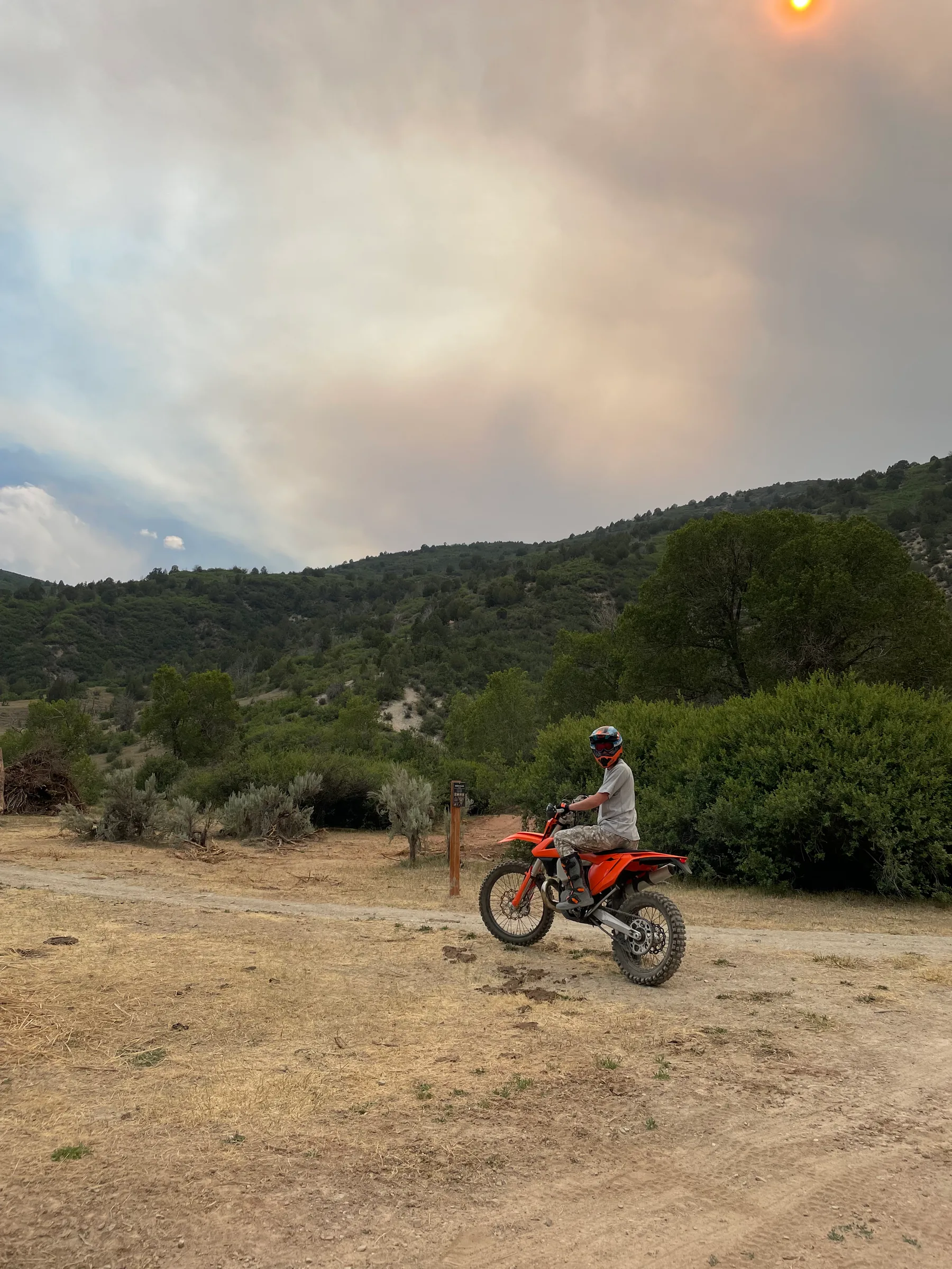 Lot paused on an orange dirt bike on a mountain trail.