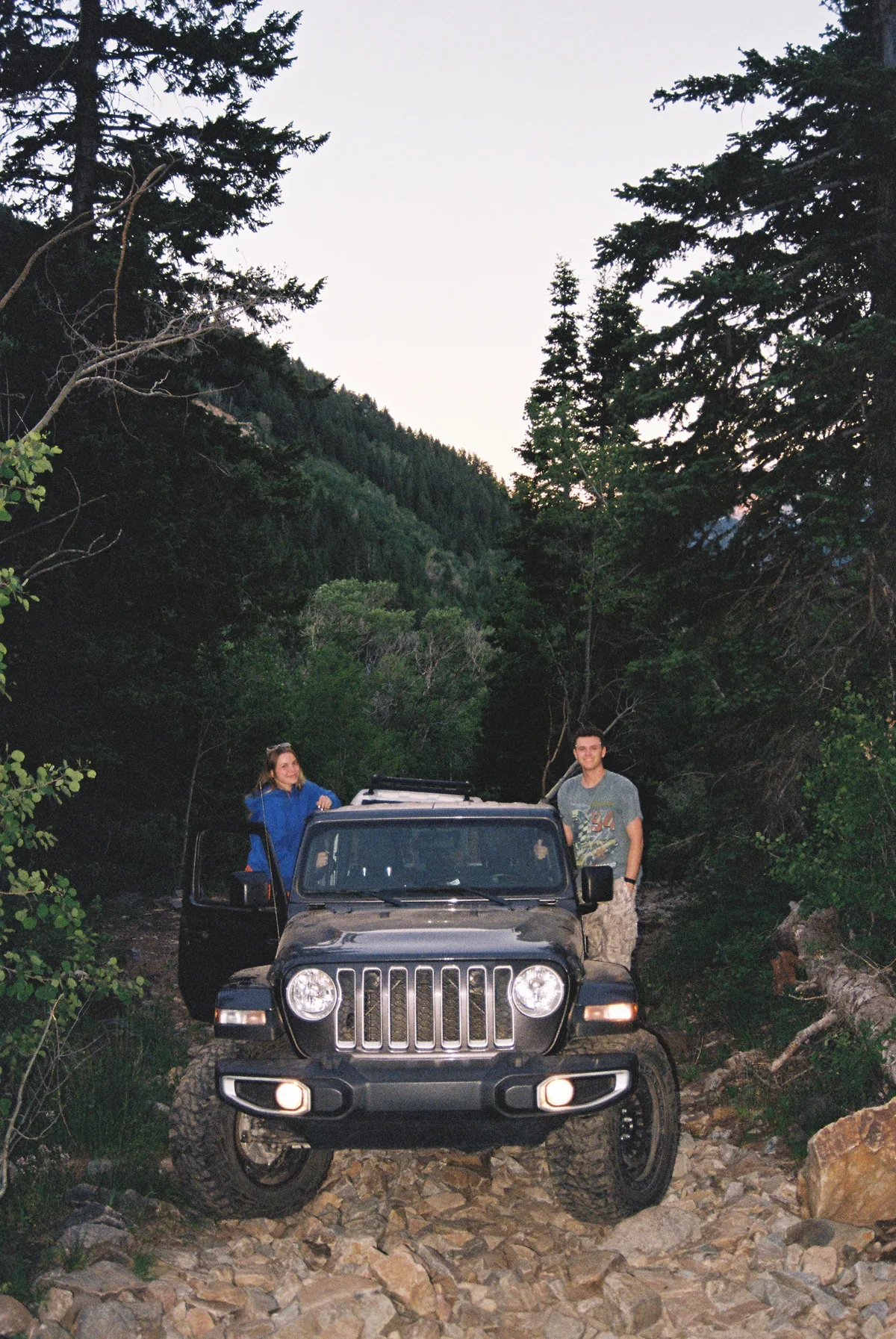Lot standing beside a Jeep with a companion on a mountain trail.