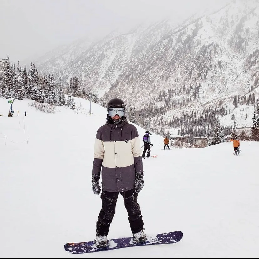 Lot standing with his snowboard at a snowy mountain resort.